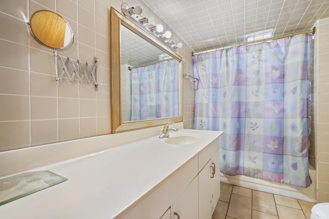 bathroom featuring tile patterned flooring, shower / bathtub combination with curtain, vanity, and tile walls
