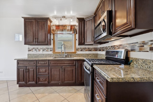 kitchen with appliances with stainless steel finishes, a sink, light tile patterned floors, dark brown cabinetry, and backsplash