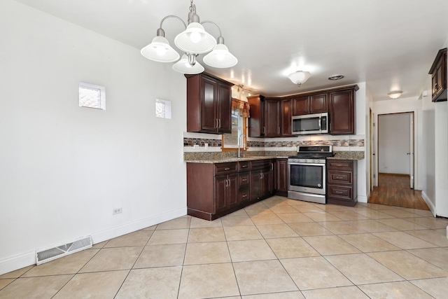 kitchen with stainless steel appliances, decorative backsplash, a sink, light tile patterned flooring, and dark brown cabinets