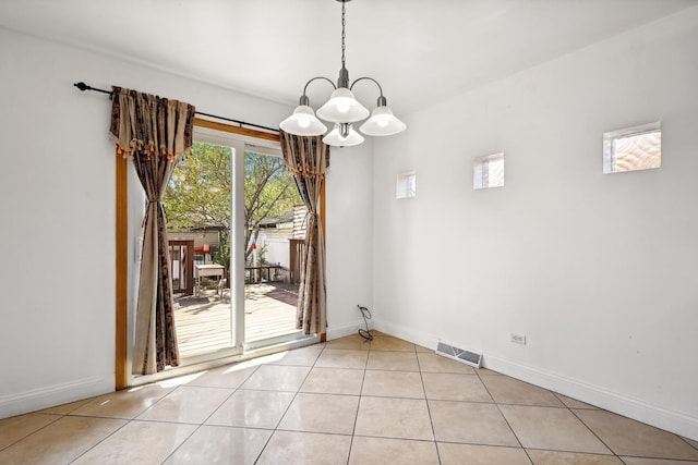 unfurnished dining area with a chandelier, light tile patterned flooring, and baseboards