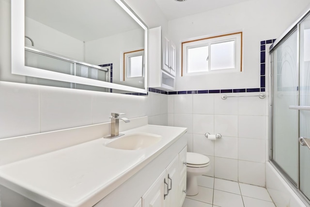 bathroom with tile walls, toilet, vanity, tile patterned floors, and shower / bath combination with glass door