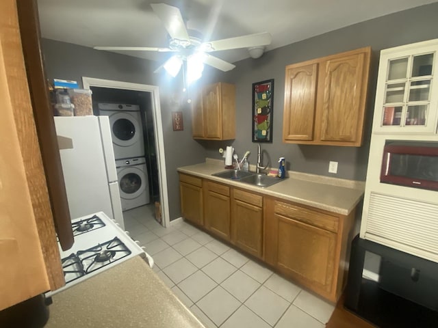 kitchen featuring stacked washer / drying machine, a sink, light tile patterned floors, freestanding refrigerator, and light countertops