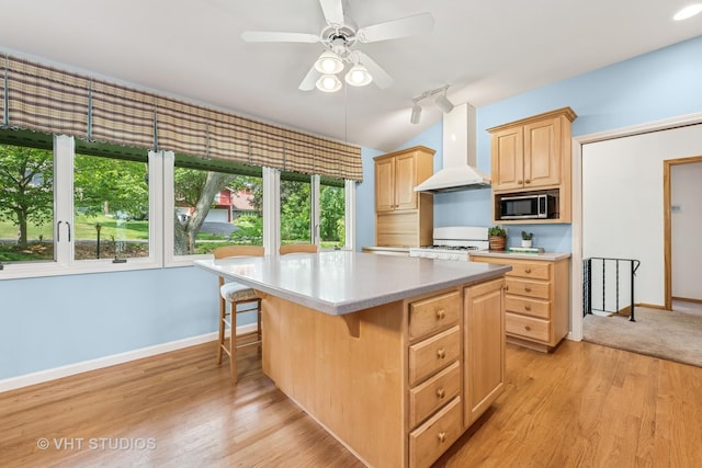 907 Division St, Barrington, IL 60010 - kitchen featuring stainless steel microwave, light brown cabinetry, wall chimney exhaust hood, light countertops, and a center island
