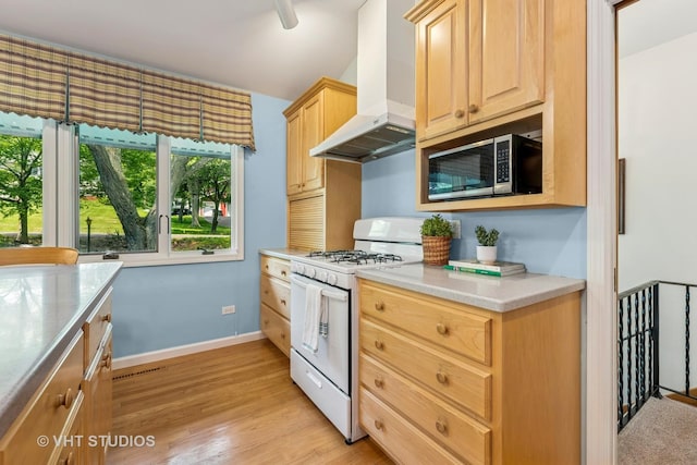907 Division St, Barrington, IL 60010 - kitchen featuring white gas range, wall chimney exhaust hood, stainless steel microwave, and light brown cabinetry