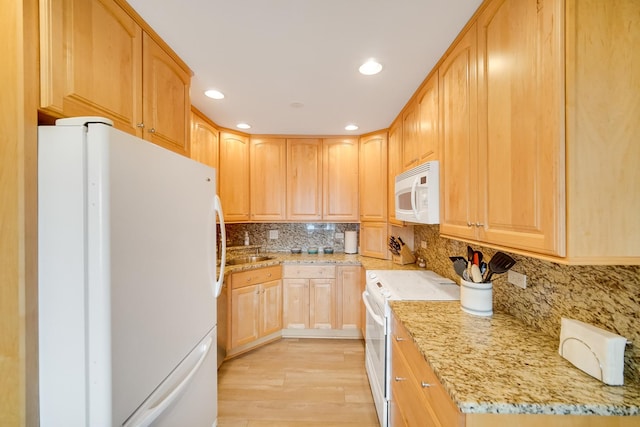 kitchen featuring white appliances, light brown cabinetry, light wood-type flooring, light stone countertops, and decorative backsplash