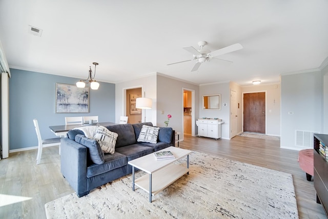 living area featuring light wood finished floors, ornamental molding, baseboards, and ceiling fan