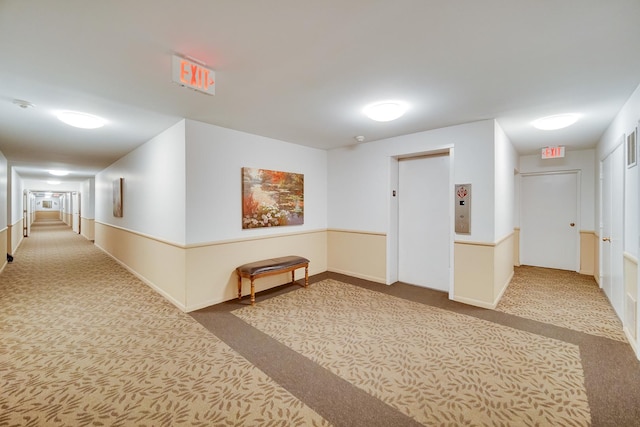 hall featuring carpet floors, elevator, and baseboards