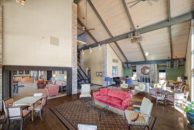 living area featuring high vaulted ceiling, wood finished floors, a fireplace, stairway, and a ceiling fan