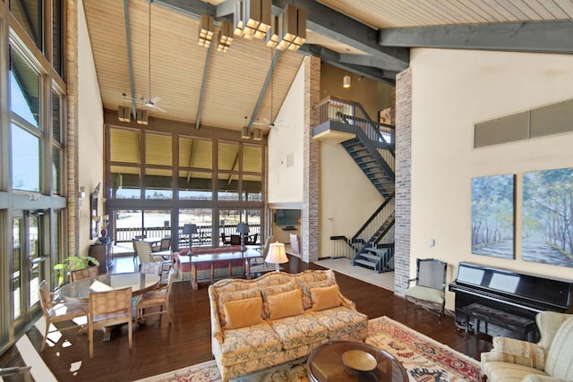 living area with high vaulted ceiling, stairs, beamed ceiling, wood finished floors, and healthy amount of natural light