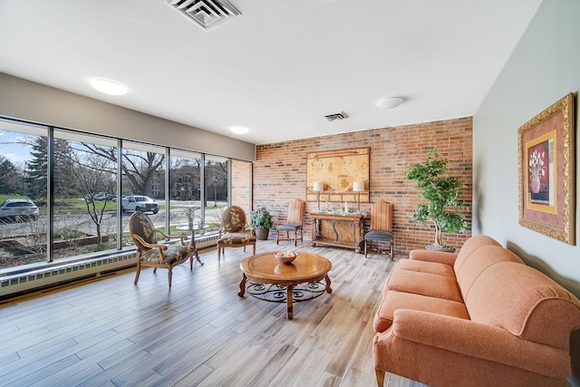 living area featuring brick wall and light wood finished floors