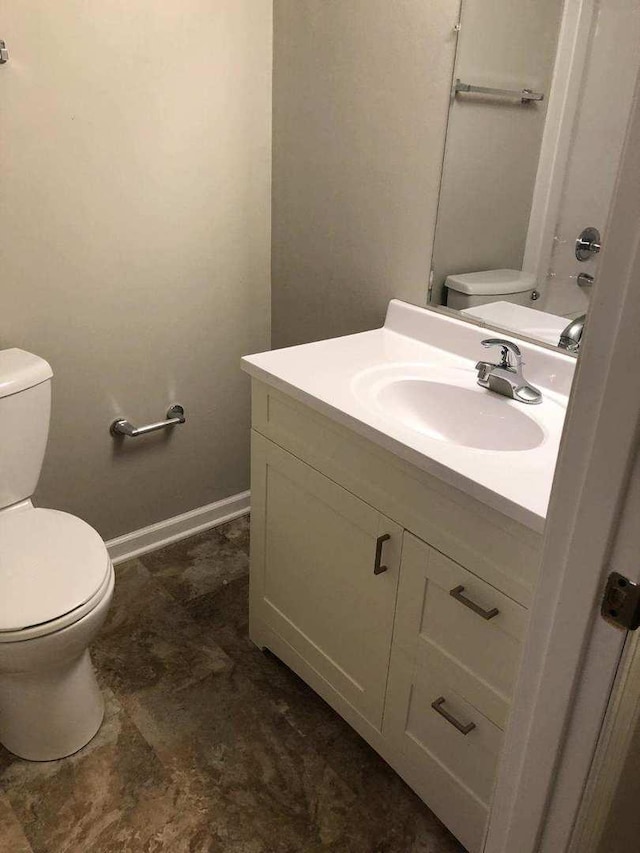 half bath with toilet, vanity, and baseboards
