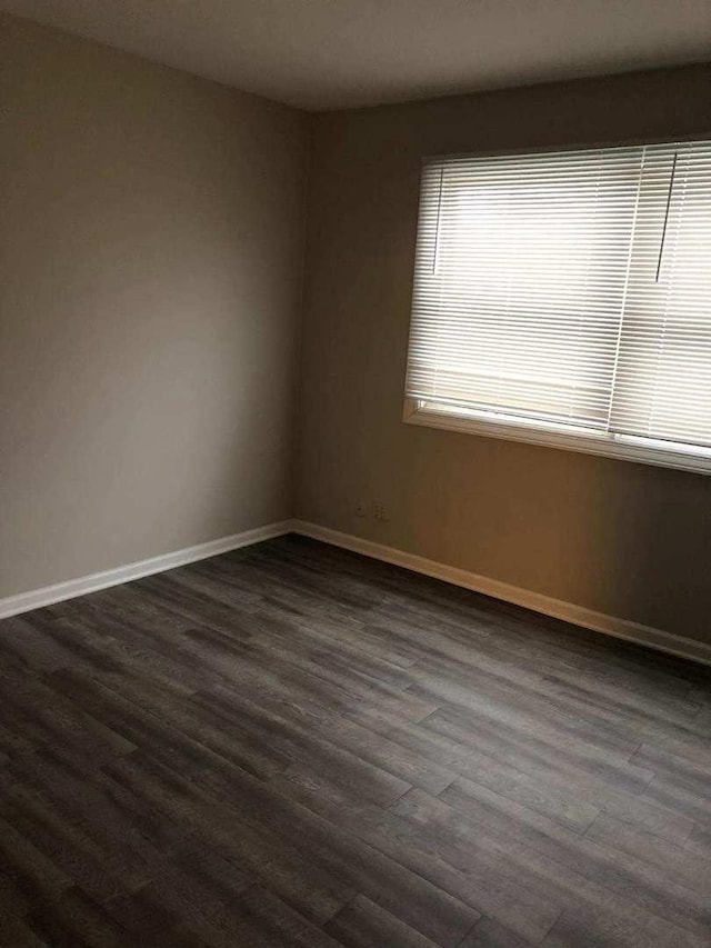 spare room with dark wood-style flooring and baseboards