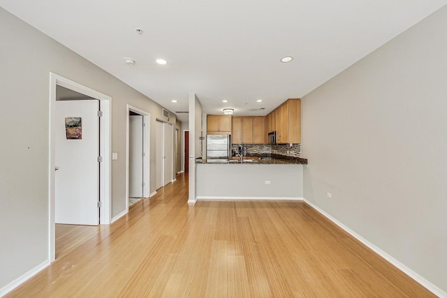 kitchen featuring stainless steel refrigerator, light wood-style flooring, tasteful backsplash, a sink, and recessed lighting