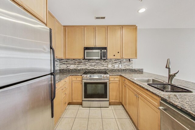 kitchen featuring stainless steel appliances, light brown cabinets, a sink, light tile patterned floors, and tasteful backsplash