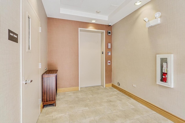 corridor featuring light tile patterned floors, recessed lighting, and a tray ceiling