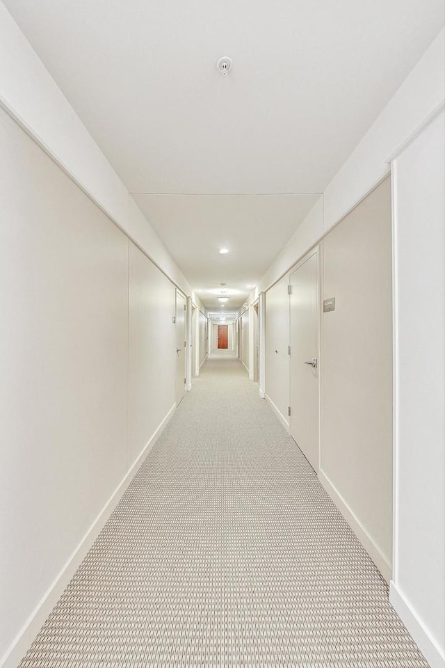 hall with baseboards and light colored carpet