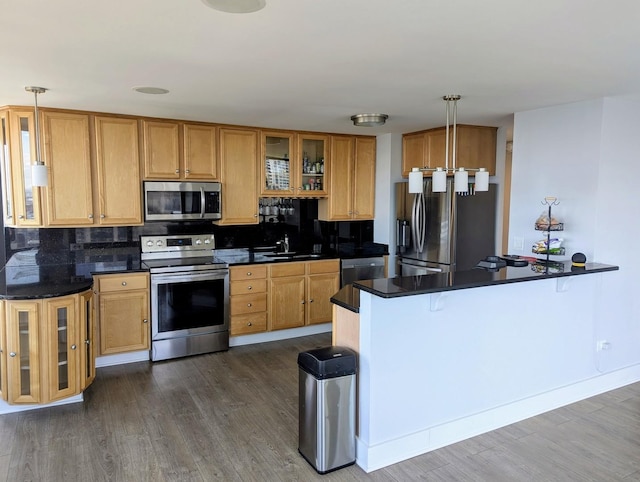 kitchen featuring appliances with stainless steel finishes, dark countertops, dark wood-style floors, and decorative backsplash