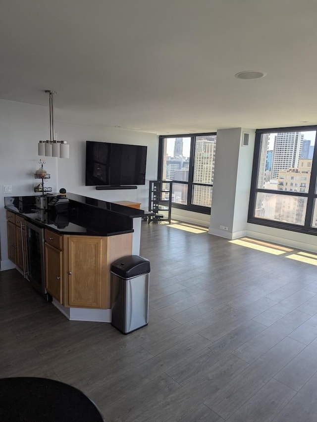 kitchen featuring dark wood finished floors, open floor plan, dark countertops, wine cooler, and brown cabinets