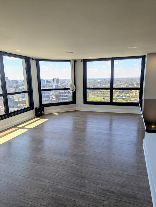spare room with dark wood-style flooring, baseboards, and a city view
