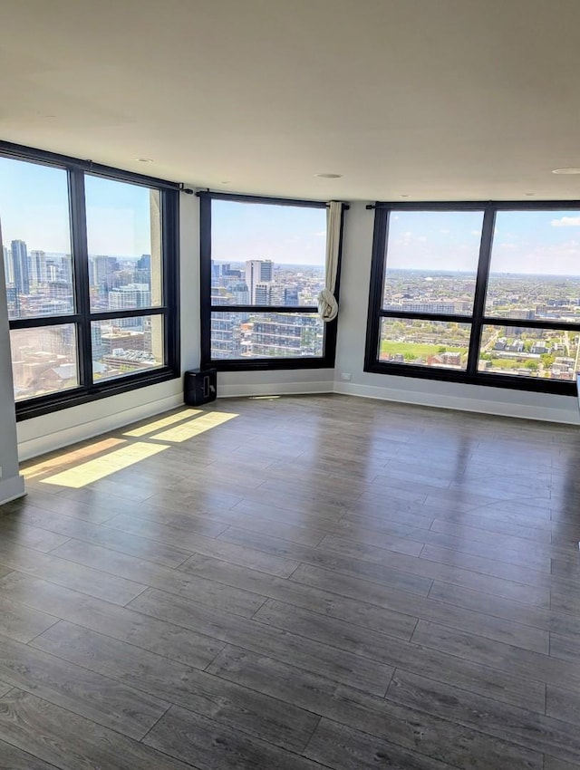 empty room featuring a view of city, healthy amount of natural light, and dark wood-style flooring