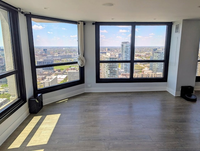 empty room featuring a city view, wood finished floors, and baseboards