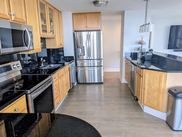 kitchen with appliances with stainless steel finishes, a sink, decorative backsplash, beverage cooler, and glass insert cabinets