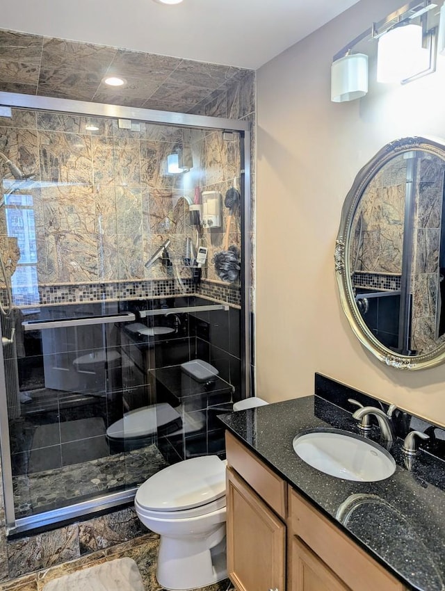 bathroom with toilet, vanity, and a shower stall