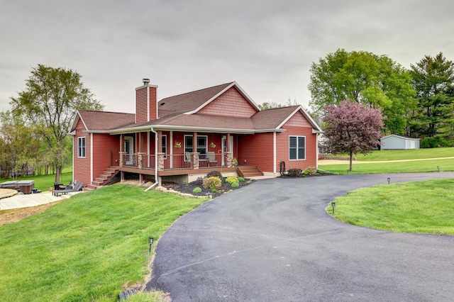view of front facade featuring a chimney, covered porch, a front lawn, and asphalt driveway