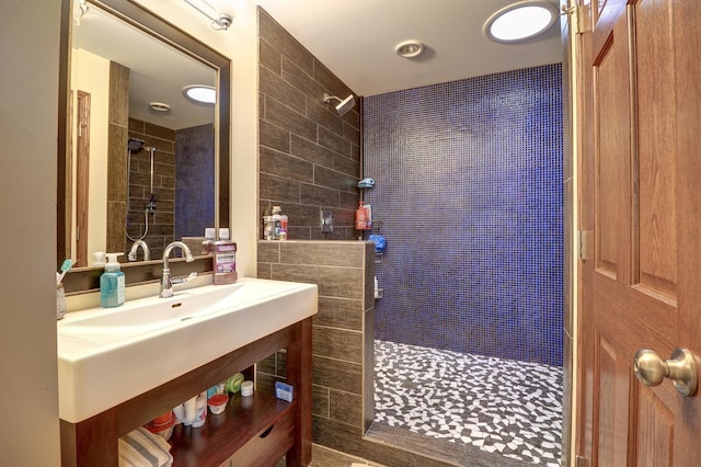 bathroom featuring tiled shower and vanity