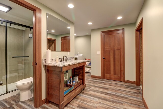 bathroom featuring wood finished floors, toilet, a shower stall, baseboards, and recessed lighting