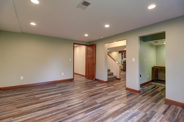 spare room with wood finished floors, baseboards, recessed lighting, and stairway