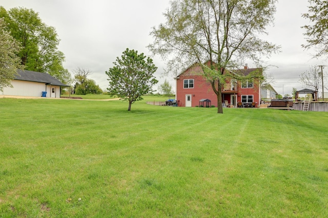 view of green lawn featuring a hot tub