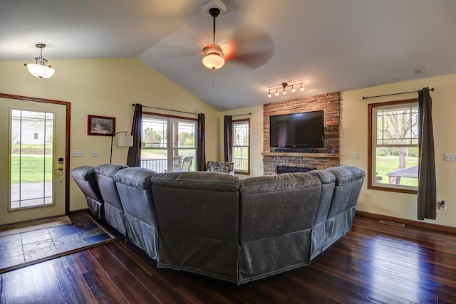living room featuring a ceiling fan, lofted ceiling, plenty of natural light, dark wood-type flooring, and a fireplace