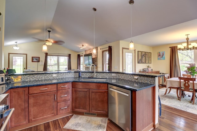 kitchen featuring appliances with stainless steel finishes, a sink, dark wood finished floors, vaulted ceiling, and a chandelier
