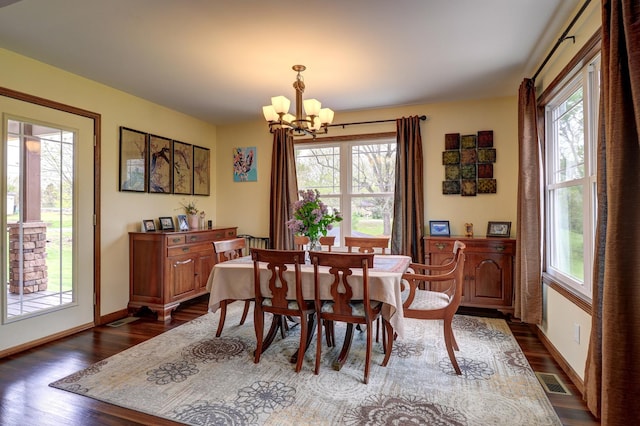 dining area featuring plenty of natural light, a chandelier, dark wood finished floors, and baseboards