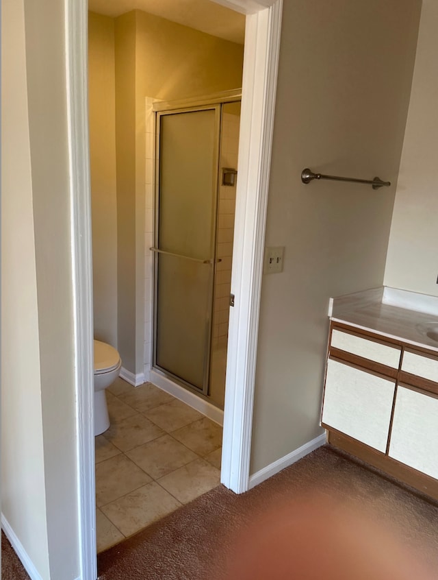bathroom featuring toilet, a shower stall, and baseboards