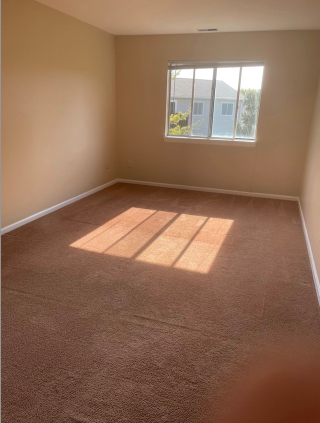 empty room featuring carpet and baseboards