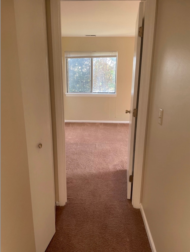 hallway with dark colored carpet and baseboards
