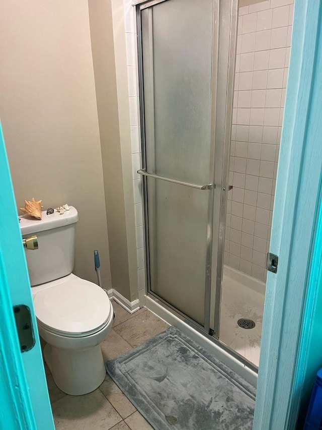 bathroom featuring a stall shower, toilet, and tile patterned flooring
