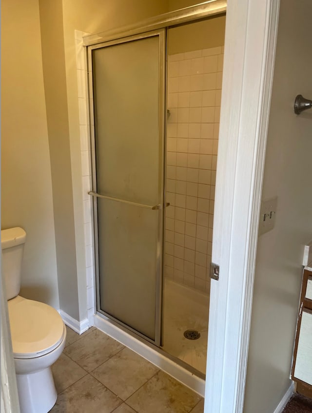 full bath with toilet, a stall shower, tile patterned floors, and baseboards