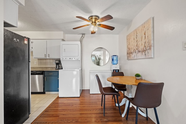 9935 El Cameno Real Dr Unit 3D, Orland Park, IL 60462 - kitchen featuring a textured ceiling, ceiling fan, stacked washing maching and dryer, blue cabinetry, and stainless steel appliances