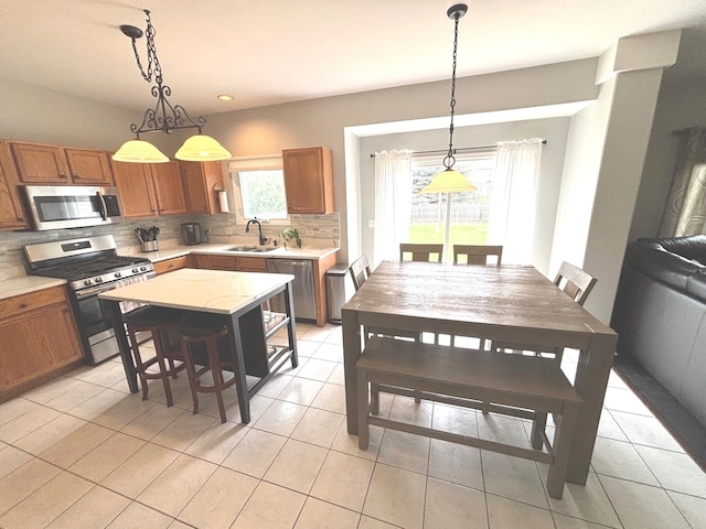 1932 Royal Ln, Aurora, IL 60503 - kitchen with stainless steel appliances, a sink, light countertops, decorative backsplash, and brown cabinets