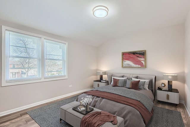 bedroom with baseboards, wood finished floors, and lofted ceiling
