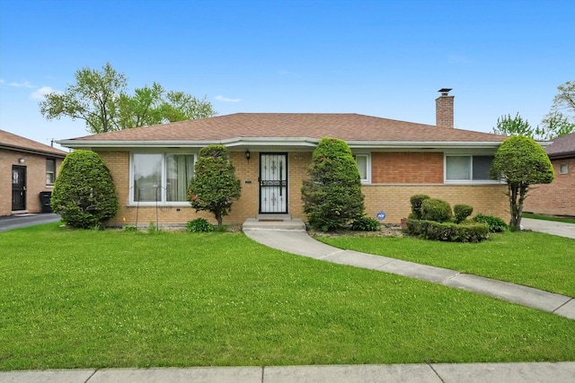 single story home with a chimney, a front lawn, and brick siding