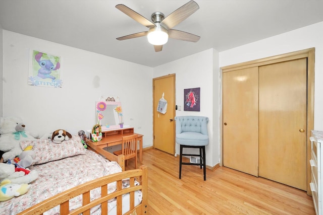 bedroom with light wood-type flooring, ceiling fan, and a closet