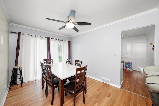 dining space with a ceiling fan, light wood-style flooring, crown molding, and baseboards