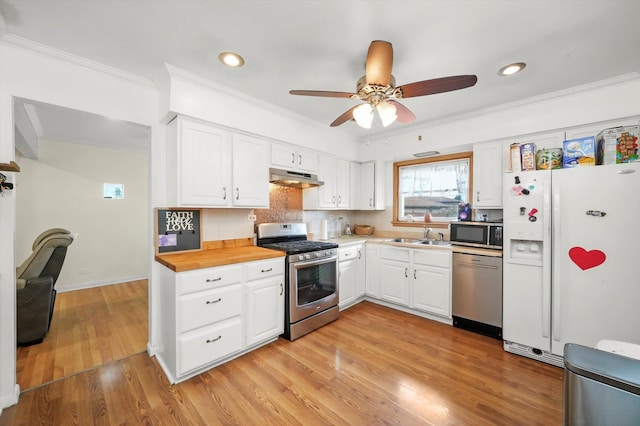 kitchen featuring stainless steel appliances, under cabinet range hood, crown molding, ceiling fan, and white cabinetry