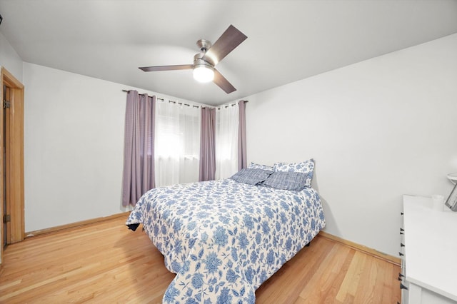 bedroom with light wood-style flooring, a ceiling fan, and baseboards