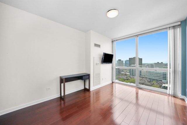 unfurnished living room with floor to ceiling windows, wood finished floors, and baseboards