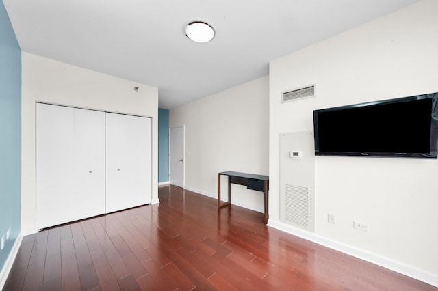 unfurnished bedroom with wood finished floors, a closet, and baseboards